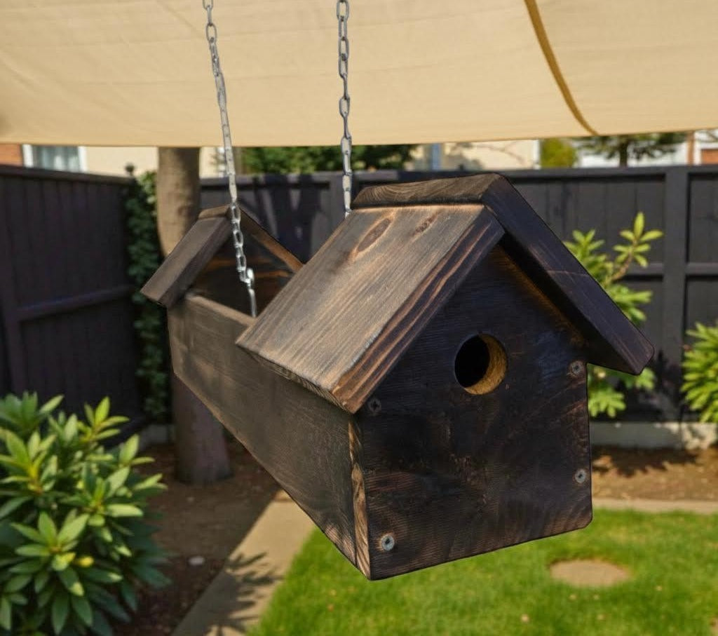 Wooden birdhouse hanging from a chain in a garden setting