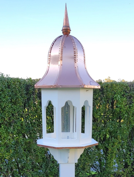 Amish handmade birdhouse with a copper roof in an elegant octagon design, mounted on a post and set against a lush green background, perfect for outdoor feeding.